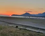 Zachód słońca nad morzem w Czarnogórze w czerwcu. Idealna pogoda na plażowanie, z górami w tle i rzędem parasoli.
