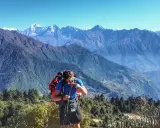 Mężczyzna z plecakiem i kijkami podczas trekkingu w Himalajach, podziwiający majestatyczne szczyty.