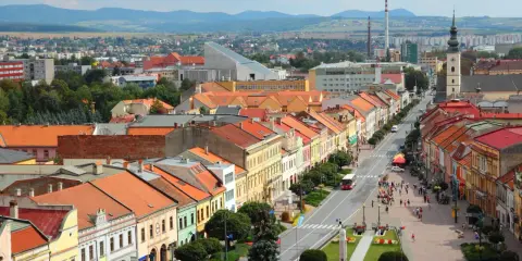 Widok na kolorowe kamienice wzdłuż ulicy, typowe dla największych miast Słowacji. W tle góry i zabudowania.