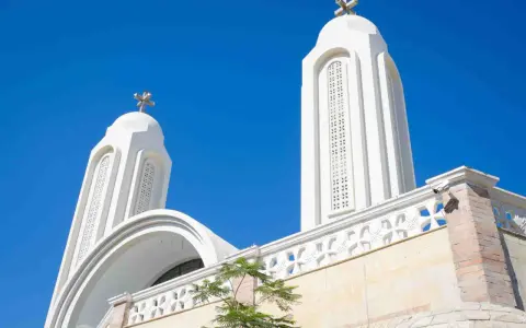 Białe wieże kościoła z krzyżami na tle błękitnego nieba. Idealna pogoda w Egipcie w sierpniu.