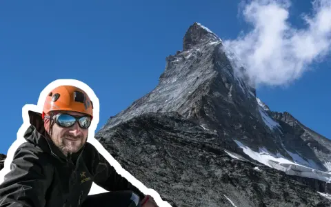 Uśmiechnięty alpinista w kasku i goglach na tle majestatycznego Matterhornu. To jego wejście na Matterhorn, cel zdobyty!