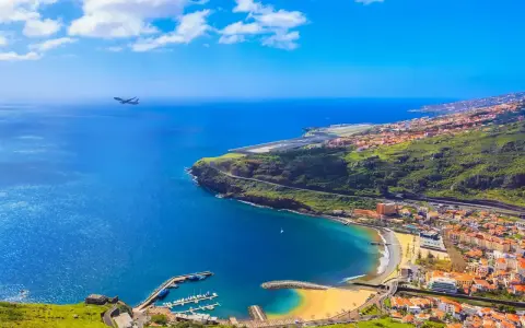 Widok na Funchal, kiedy na Maderę przylatuje samolot. Błękitne morze, plaża, port i zielone wzgórza.