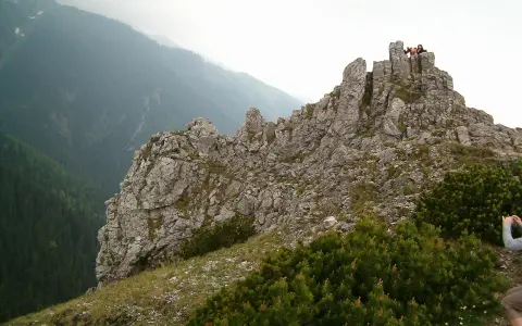 Sarnia skała trasa w Tatrach. Grupa turystów na szczycie skalistego grzbietu, podziwiająca widok na zalesioną dolinę.