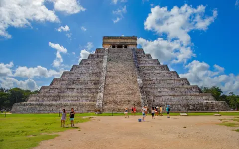 Majestatyczna piramida w Chichen Itza, z turystami podziwiającymi jej piękno na tle błękitnego nieba.