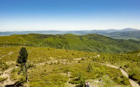 Widok z **barania góra szlak** na zielone wzgórza i niebo. Dwie osoby idą ścieżką.