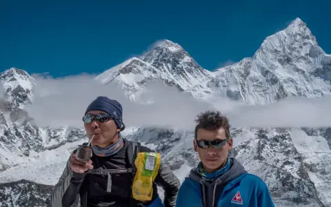 Niesamowity widok z Mount Everest. Dwóch wspinaczy odpoczywa, jeden pije yerba mate, podziwiając majestatyczne szczyty.