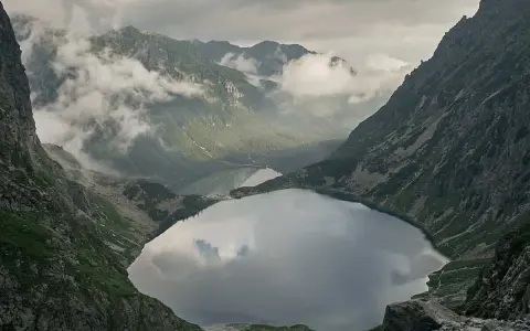 Widok na Morskie Oko, droga na Rysy w oddali. Mgła otula szczyty, odbijając się w tafli jeziora.