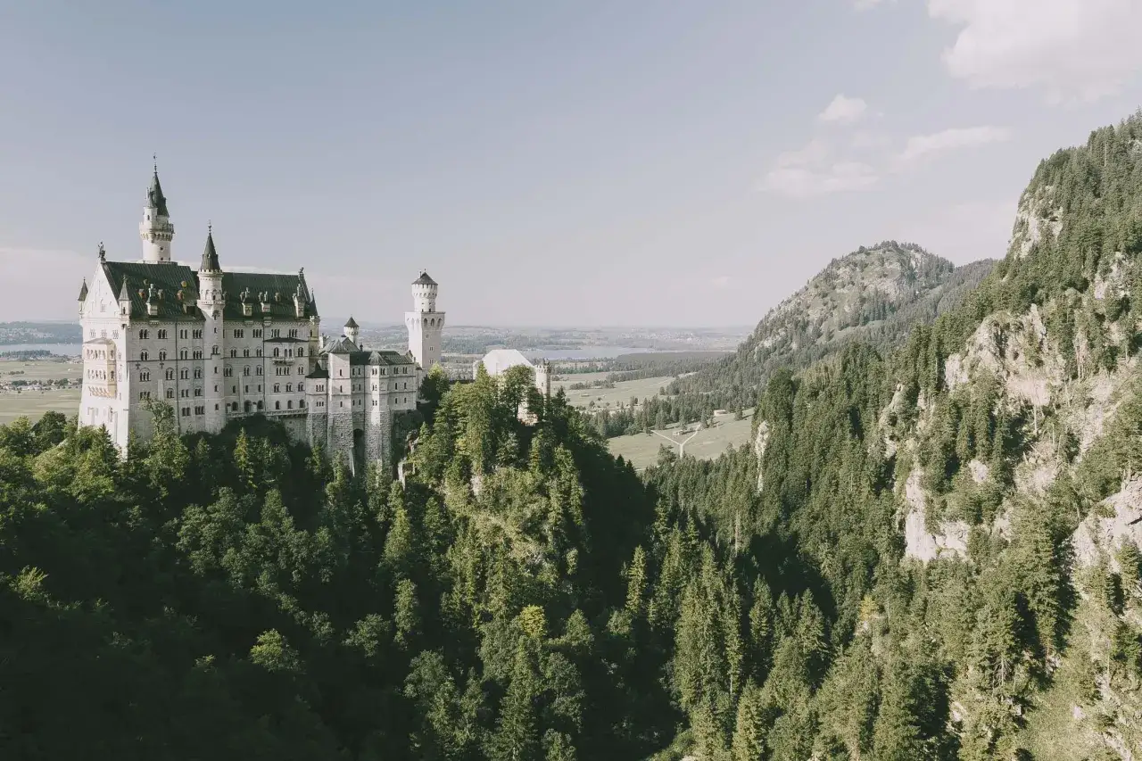 Bajkowy zamek Neuschwanstein wznosi się na skalistym wzgórzu, otoczony gęstym lasem i malowniczymi dolinami.